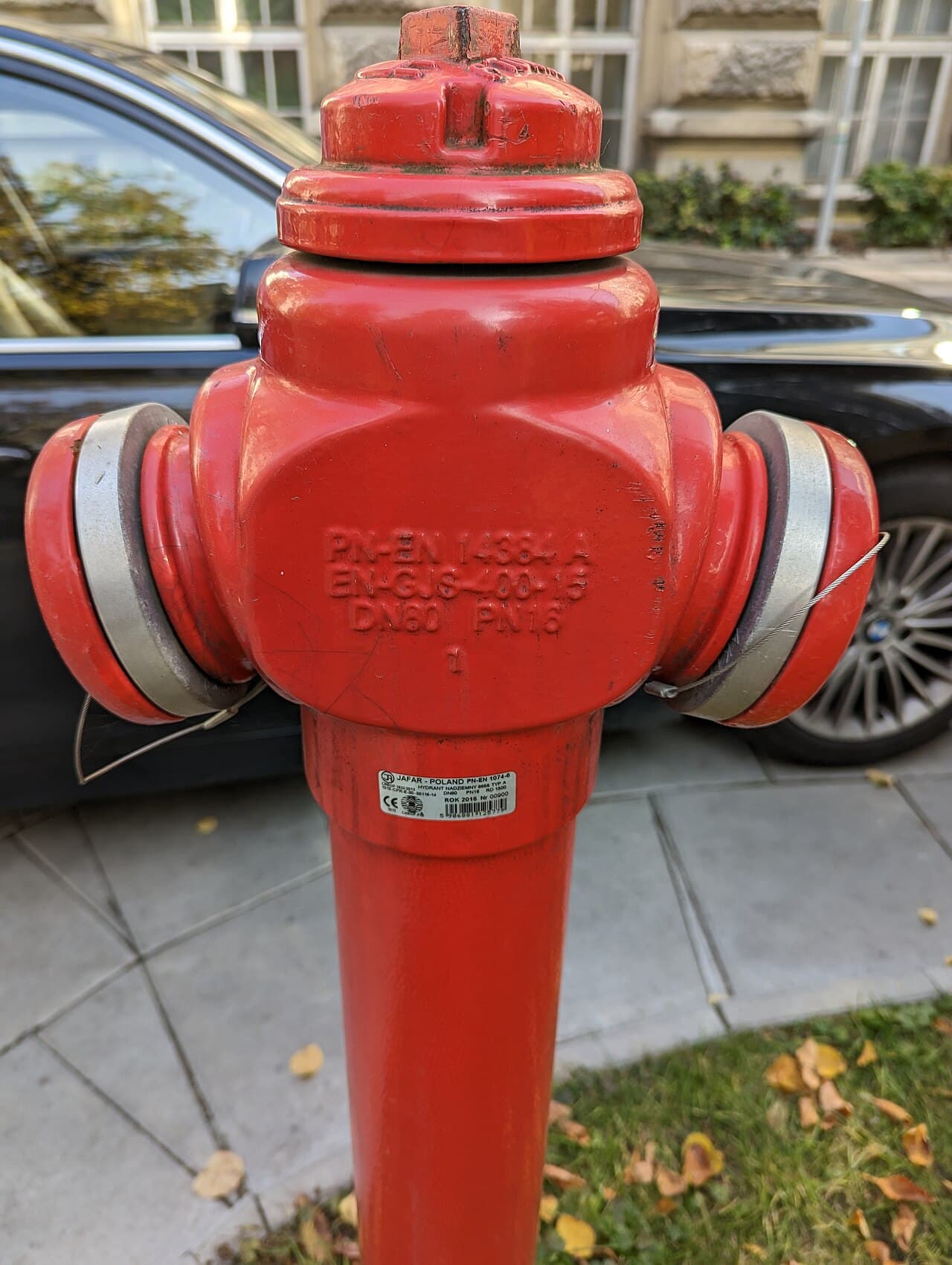 Czerwony hydrant nadziemny zgodny z PN-EN 14384 przy ulicy w Warszawie