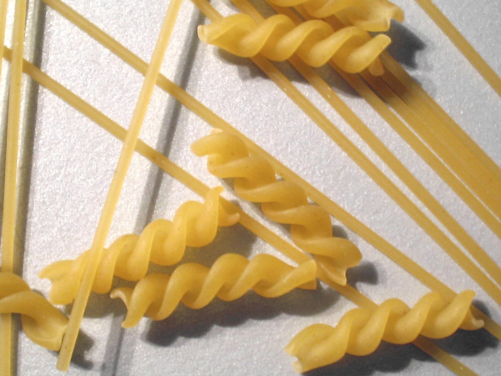 Suche spaghetti i kilka świderków rozsypane na szarej powierzchni